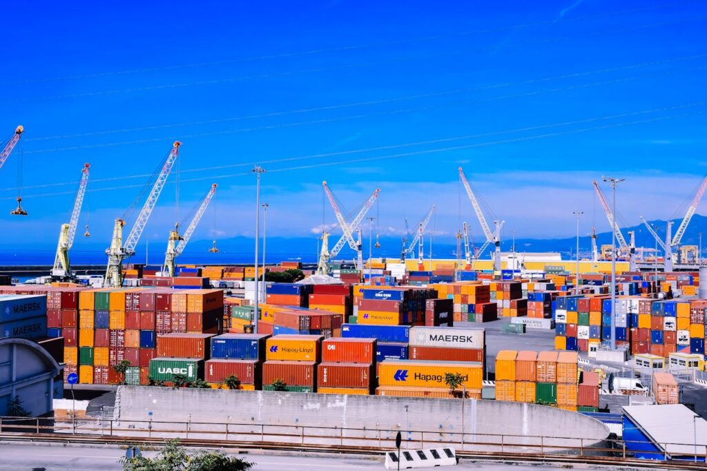 A bustling shipping port with colorful stacked containers and numerous cranes under a clear blue sky.